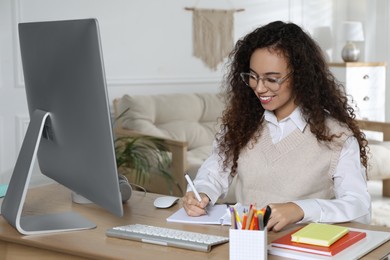 Photo of African American woman using modern computer for studying at home. Distance learning