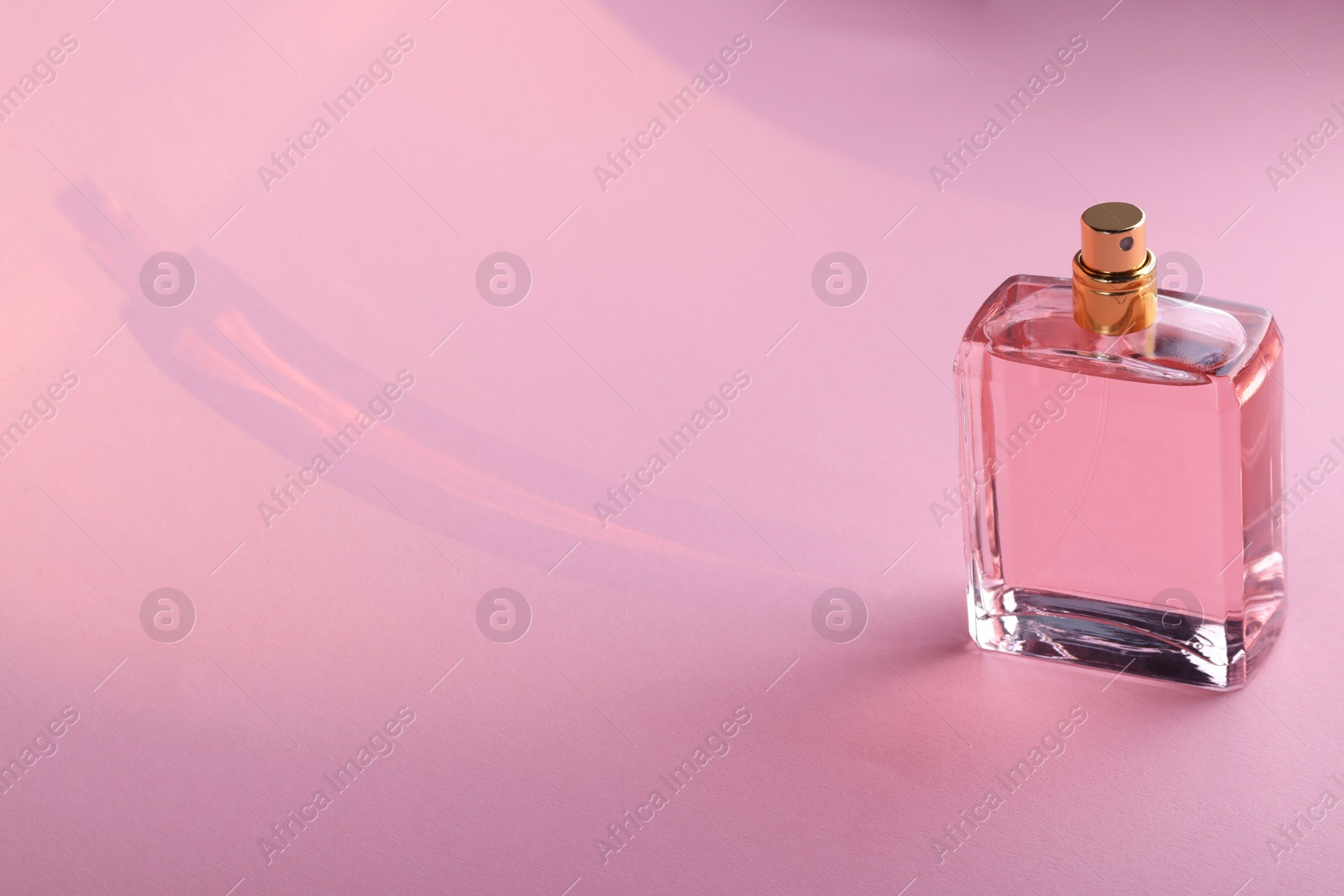Photo of Luxury women's perfume in bottle on violet background. Space for text