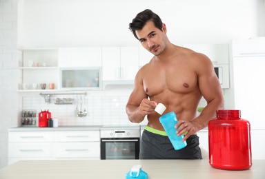 Young shirtless athletic man preparing protein shake in kitchen, space for text