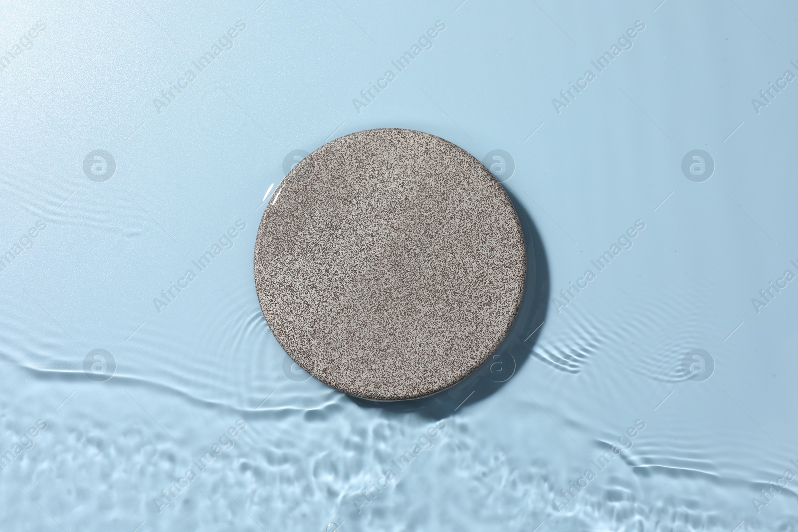 Photo of Presentation for product. Stone podium in water on light blue background, top view