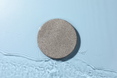 Presentation for product. Stone podium in water on light blue background, top view