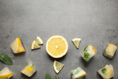 Flat lay composition with fresh juicy lemon, mint and ice cubes on grey table. Space for text