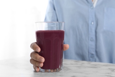 Photo of Woman with glass of fresh acai drink at white marble table, closeup