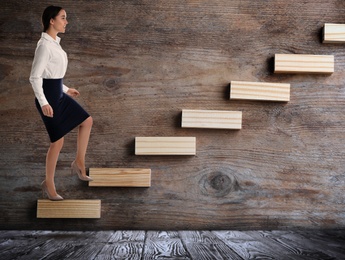 Image of Businesswoman walking up stairs against wooden background. Career ladder concept