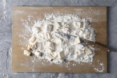 Making shortcrust pastry. Flour, butter, knife and wooden board on grey table, top view