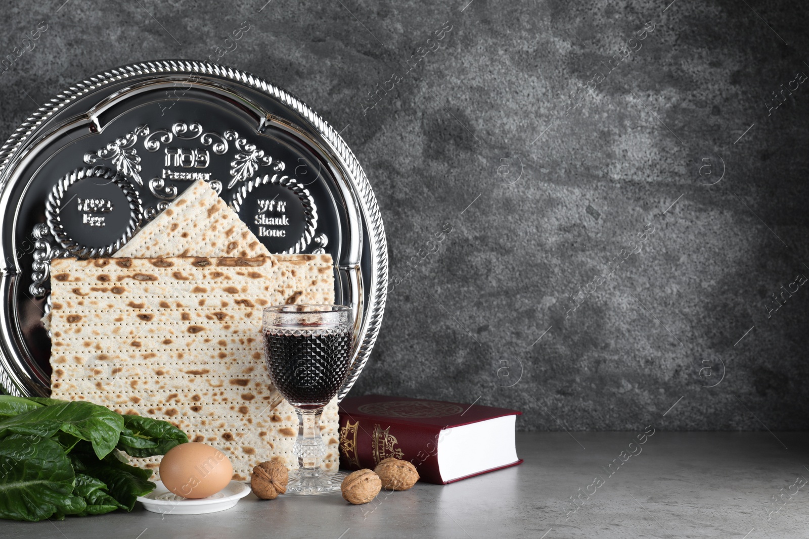 Photo of Symbolic Pesach (Passover Seder) items on grey table. Space for text