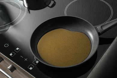 Photo of Frying pan with cooking oil on induction stove