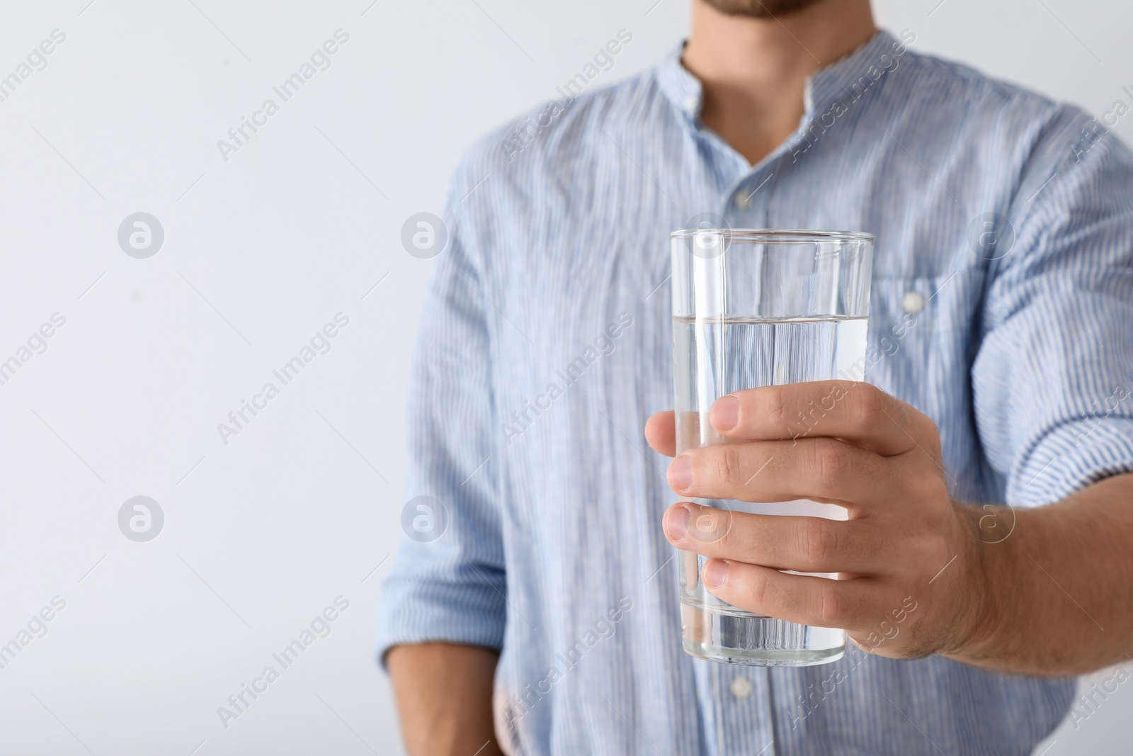 Photo of Man holding glass of pure water on white background, closeup