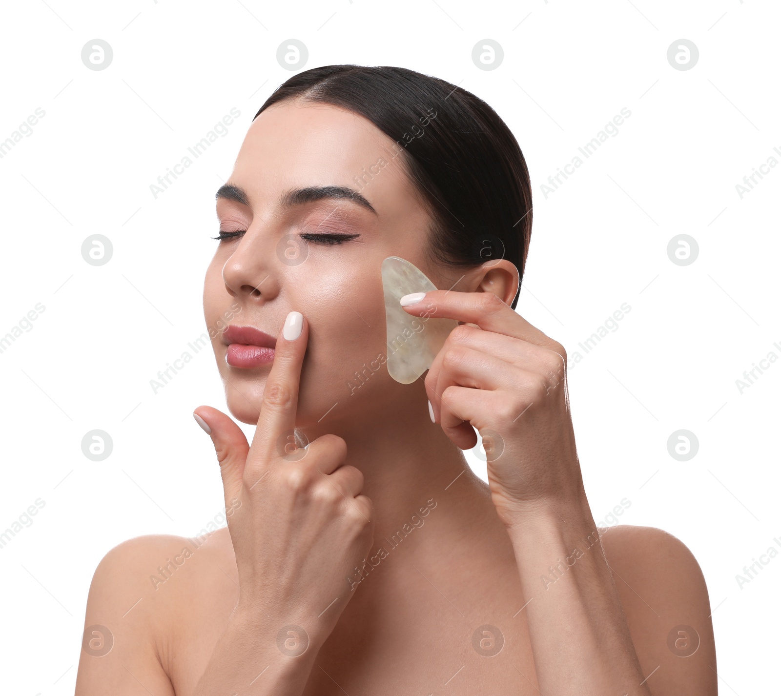 Photo of Beautiful young woman doing facial massage with gua sha tool on white background