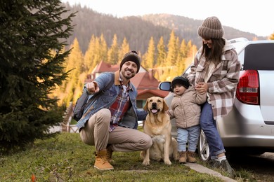 Photo of Parents, their daughter and dog near car in mountains. Family traveling with pet