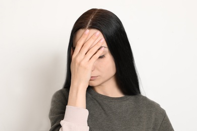 Young woman covering face against white background