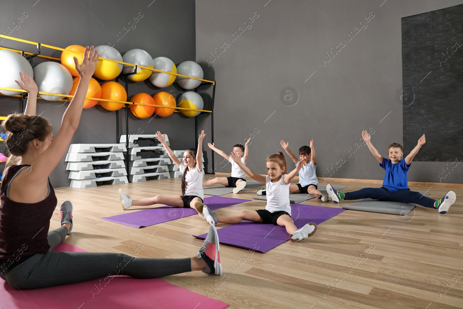 Photo of Cute little children and trainer doing physical exercise in school gym. Healthy lifestyle