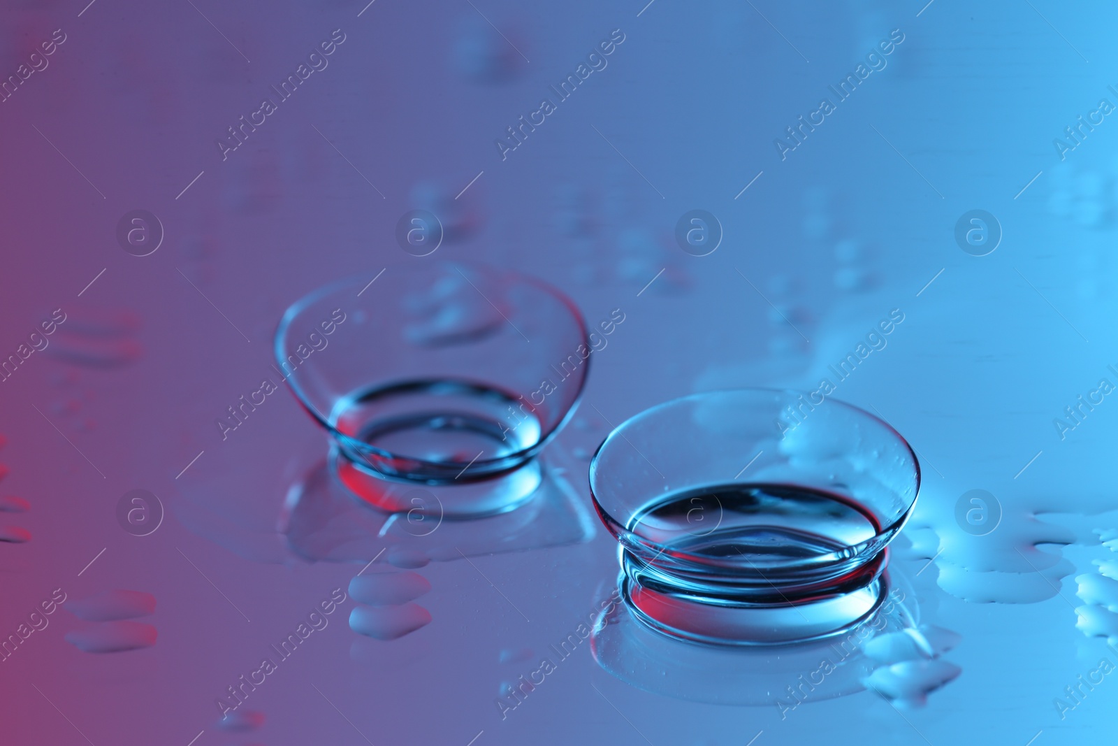 Photo of Pair of contact lenses on wet mirror surface