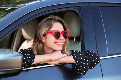 Photo of Young beautiful woman wearing heart shaped glasses in car