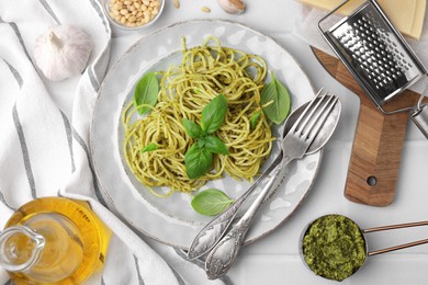 Photo of Delicious pasta with pesto sauce and basil served on white tiled table, flat lay