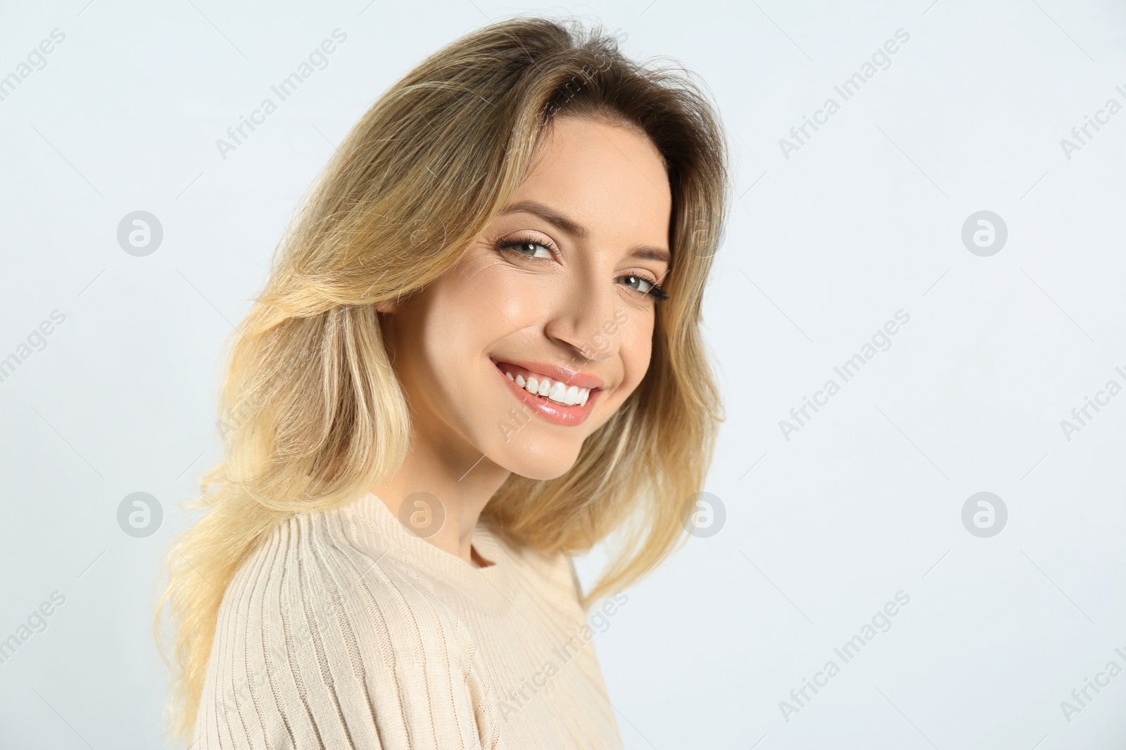 Photo of Portrait of happy young woman with beautiful blonde hair and charming smile on light background. Space for text