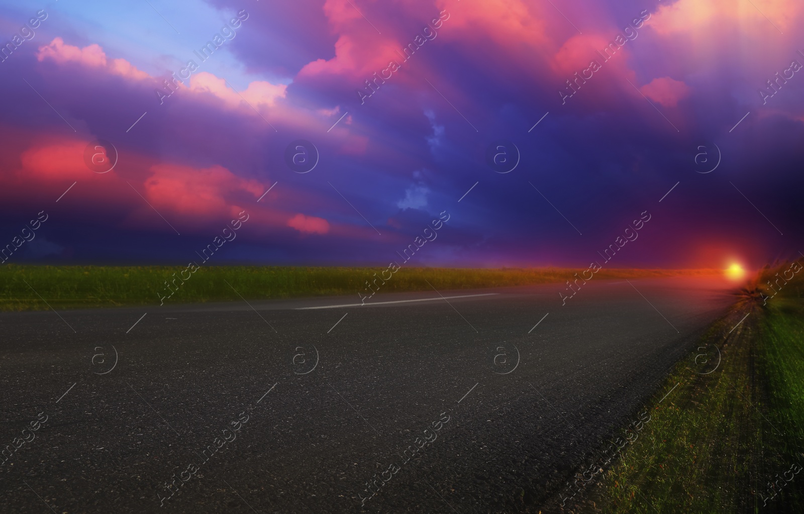 Image of Empty asphalt road through field at beautiful sunset