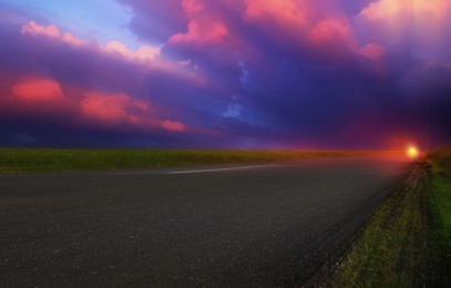 Image of Empty asphalt road through field at beautiful sunset