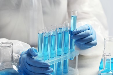 Photo of Scientist taking test tube with light blue liquid, closeup