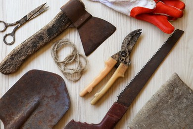 Flat lay composition with old secateurs and other gardening tools on white wooden table
