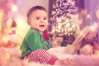 Image of Baby wearing cute elf costume on floor in room decorated for Christmas. Magical festive atmosphere