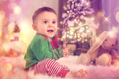 Baby wearing cute elf costume on floor in room decorated for Christmas. Magical festive atmosphere