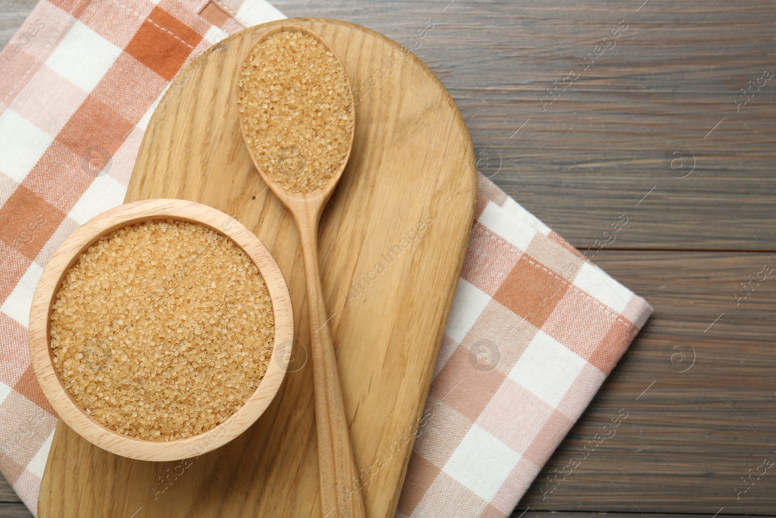 Photo of Brown sugar in bowl and spoon on wooden table, top view. Space for text