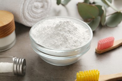 Photo of Tooth powder, brushes and dental floss on grey table, closeup