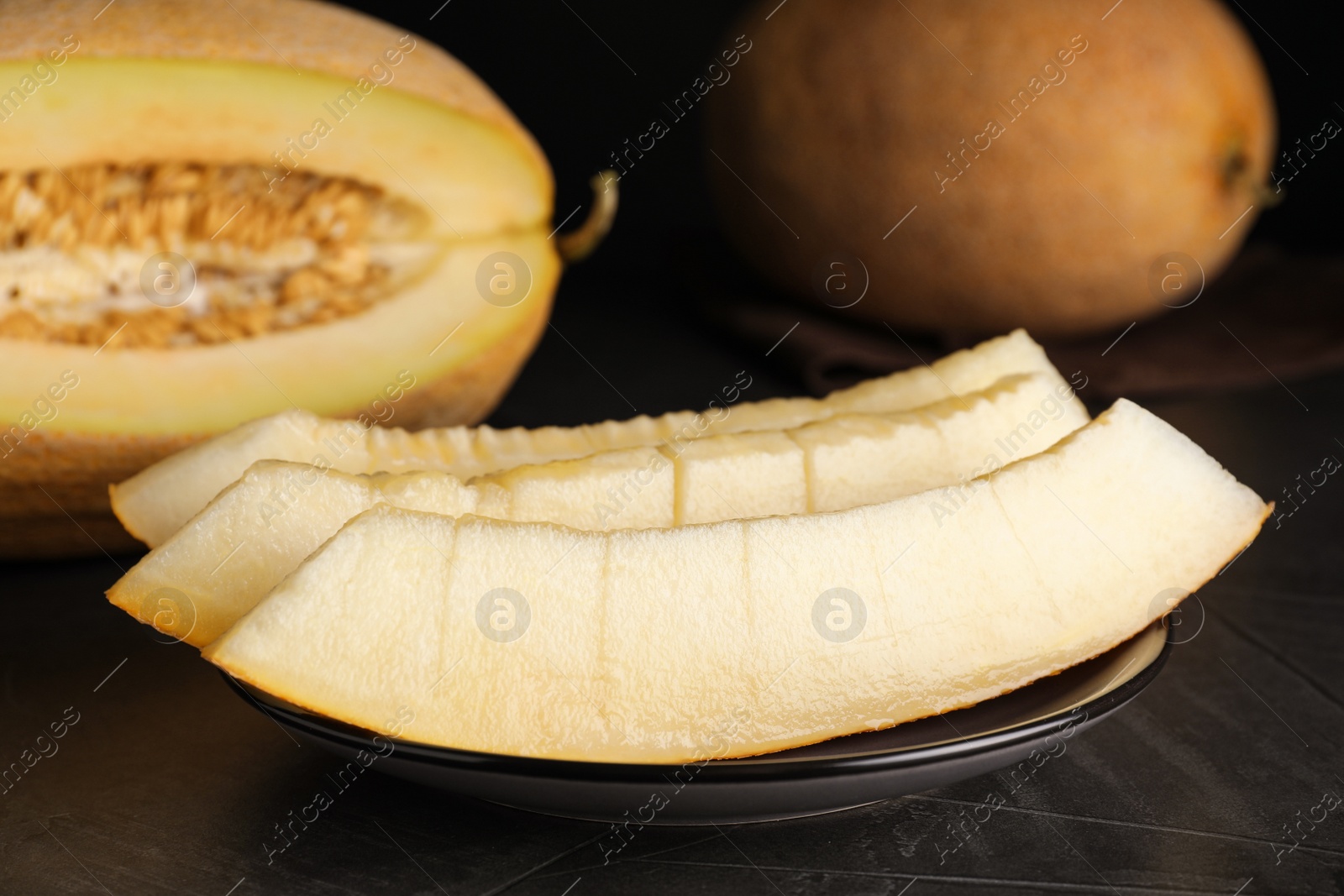 Photo of Slices of delicious honey melon on black table