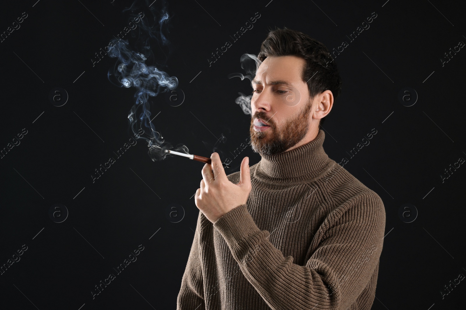 Photo of Man using cigarette holder for smoking on black background, space for text