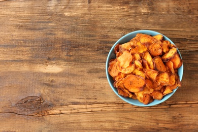 Photo of Bowl of sweet potato chips on wooden table, top view. Space for text