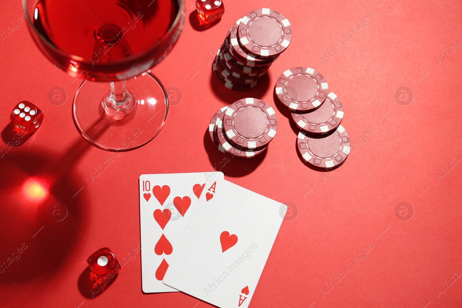 Photo of Casino chips, playing cards, dice and cocktail on red  table, flat lay