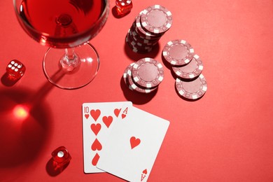 Photo of Casino chips, playing cards, dice and cocktail on red  table, flat lay