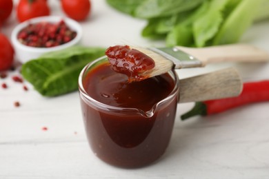 Photo of Marinade and basting brush on white table, closeup