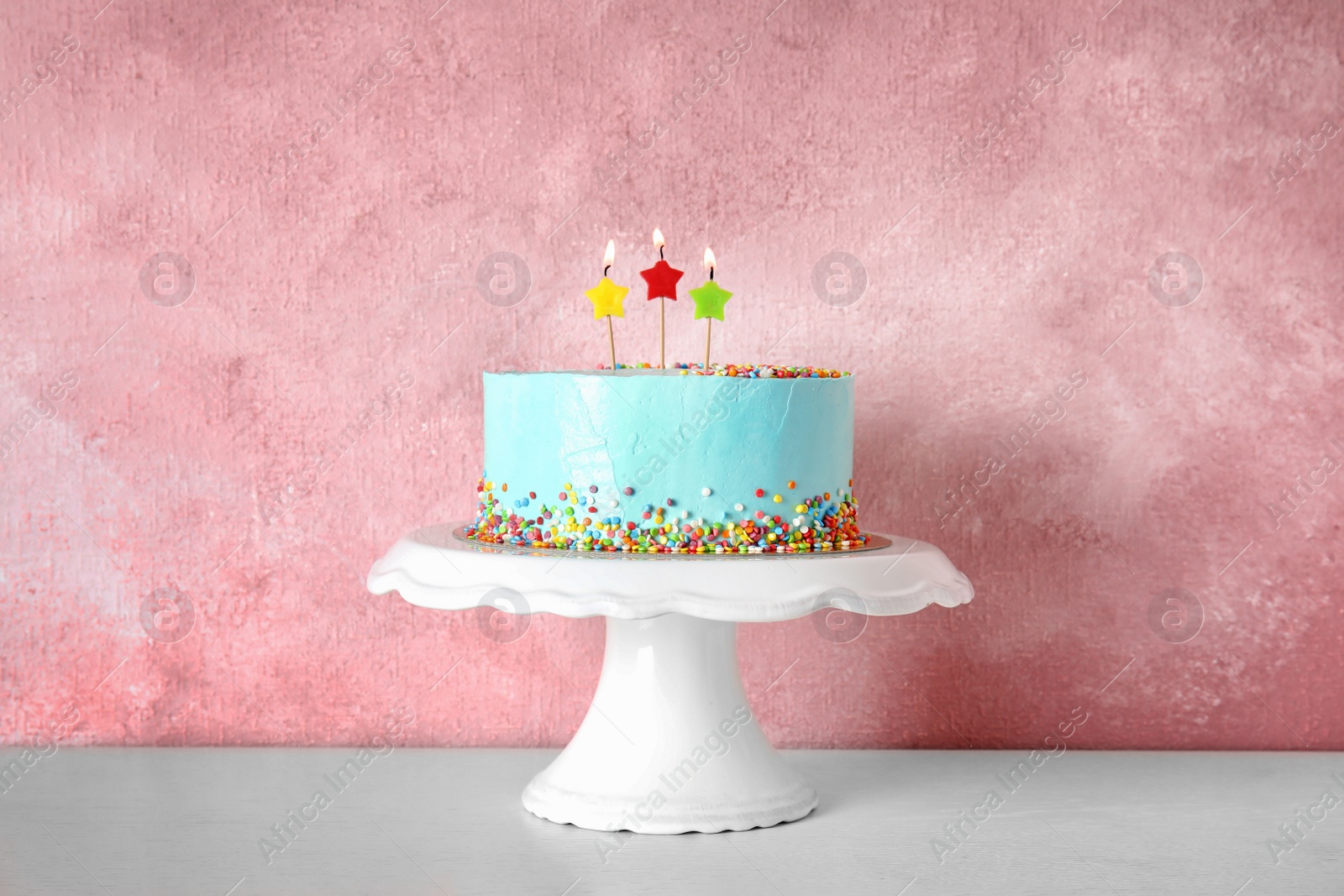 Photo of Fresh delicious birthday cake with candles on stand against color background