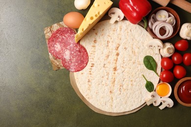 Photo of Pizza base and products on green textured table, flat lay. Space for text