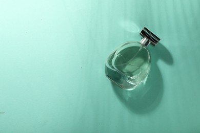 Luxury perfume in bottle on turquoise background, top view. Space for text