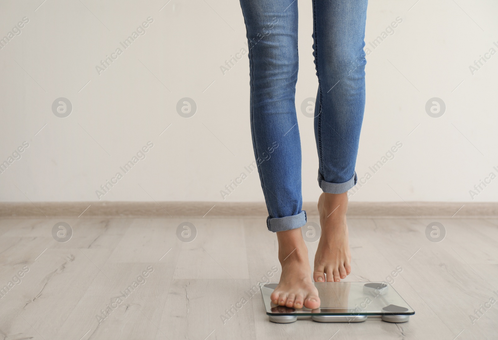 Photo of Woman measuring her weight using scales on wooden floor. Healthy diet