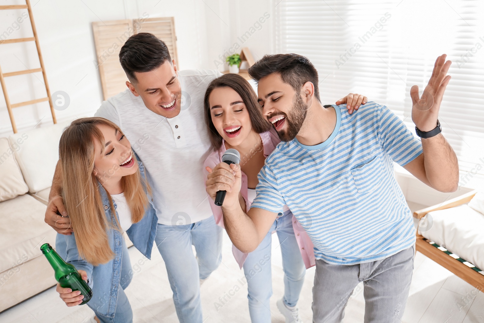 Photo of Happy friends singing karaoke together at home