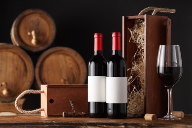 Photo of Wooden boxes, glass, corkscrew and wine bottles on table against black background