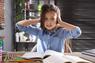 Photo of Tired preteen girl at table. Doing homework