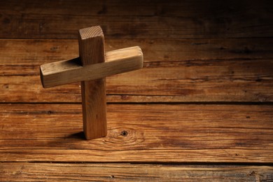 Cross on wooden table, space for text. Religion of Christianity
