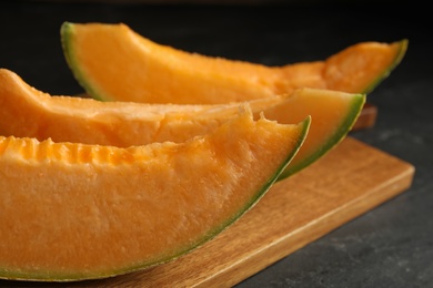 Photo of Slices of tasty fresh melon on black table, closeup