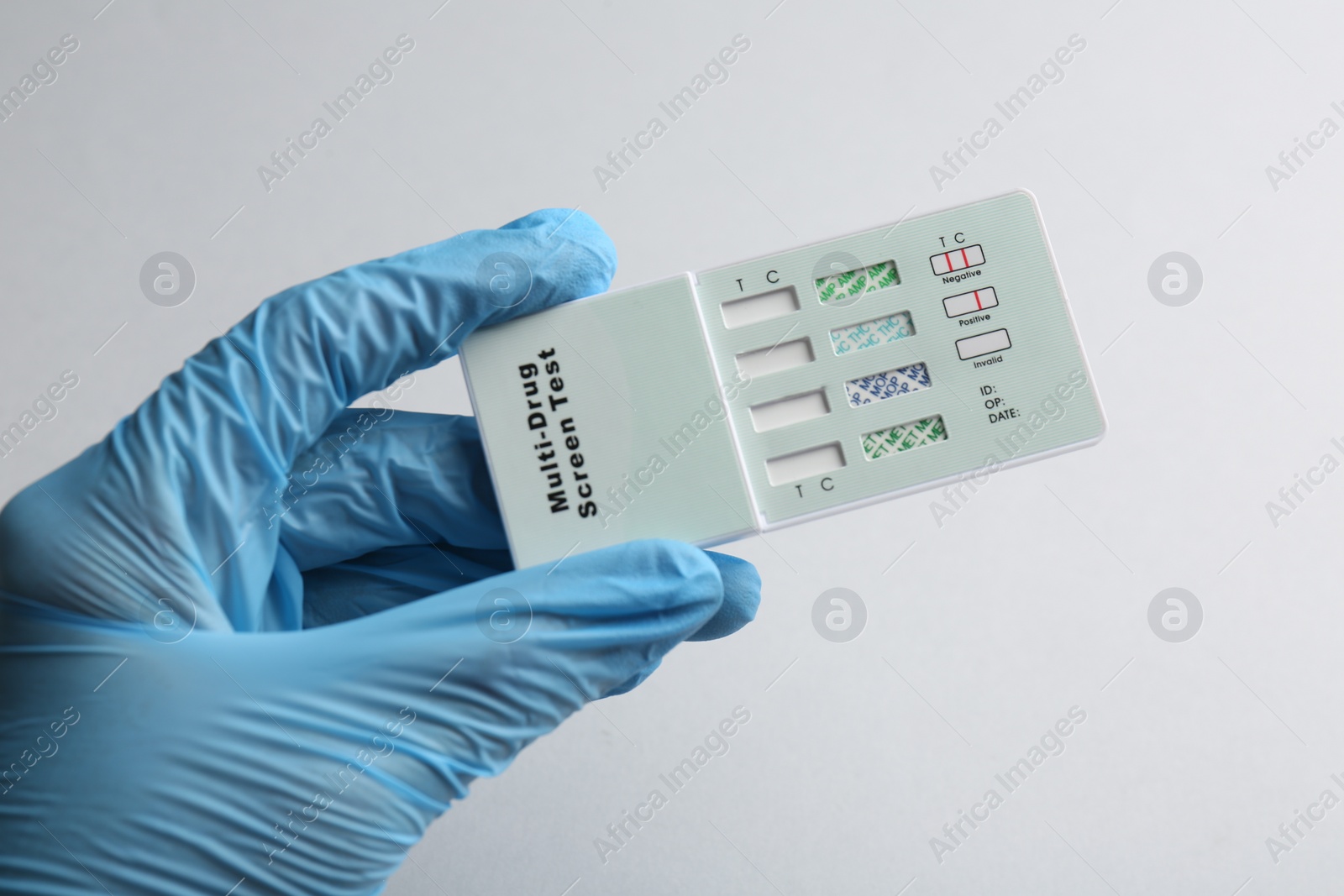 Photo of Doctor holding multi-drug screen test on light grey background, closeup