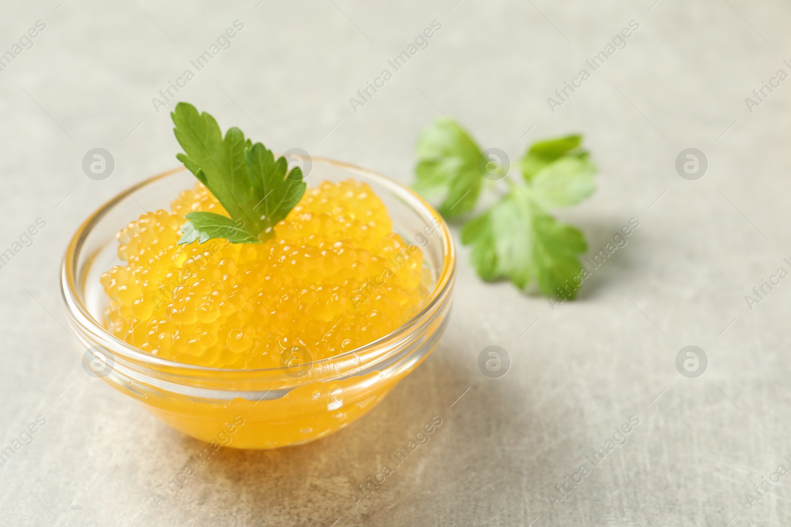 Photo of Fresh pike caviar in bowl and parsley on light grey table