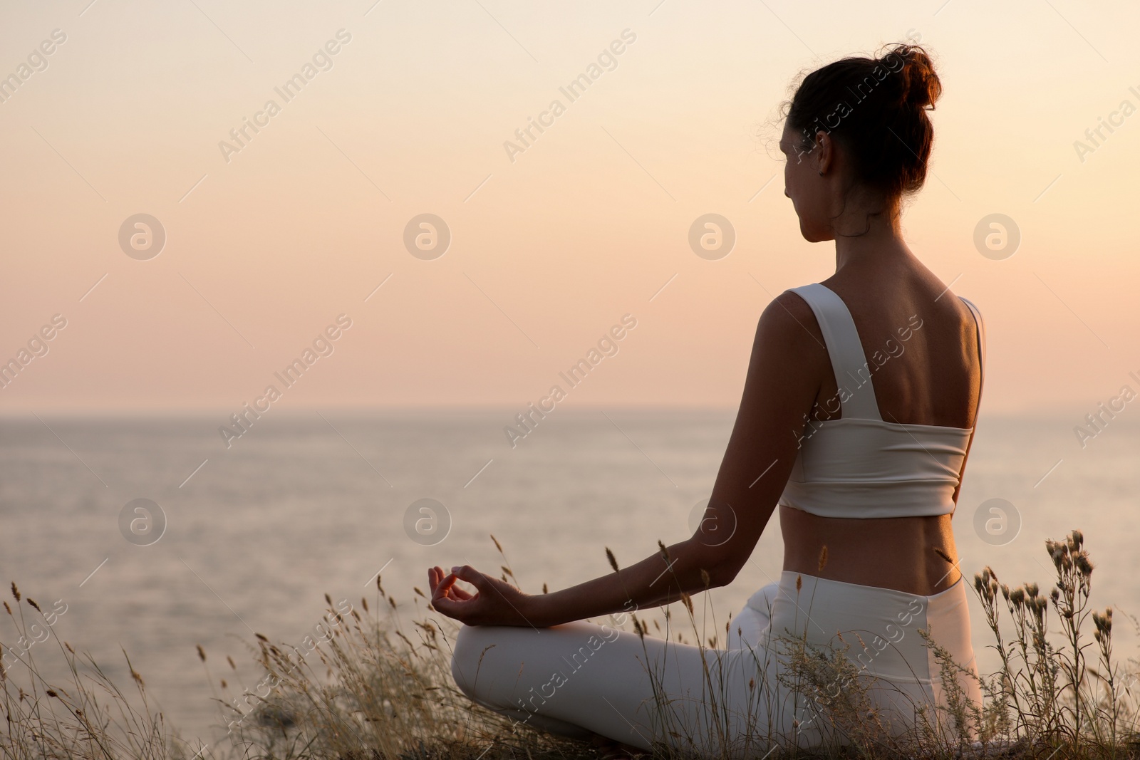 Photo of Woman meditating near sea. Space for text