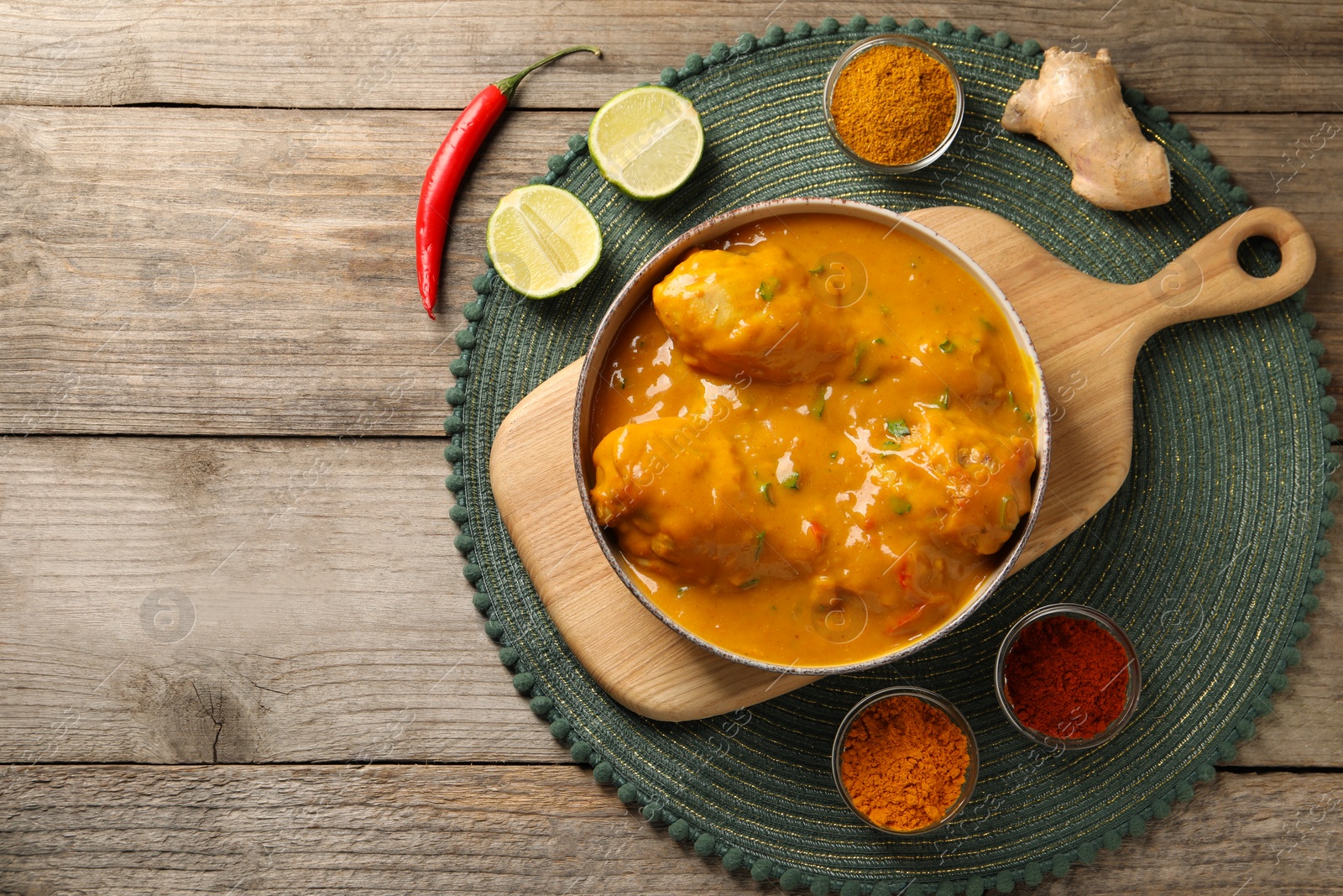 Photo of Tasty chicken curry and ingredients on wooden table, flat lay. Space for text