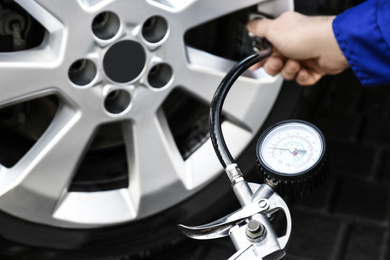 Mechanic checking tire air pressure at car service, closeup