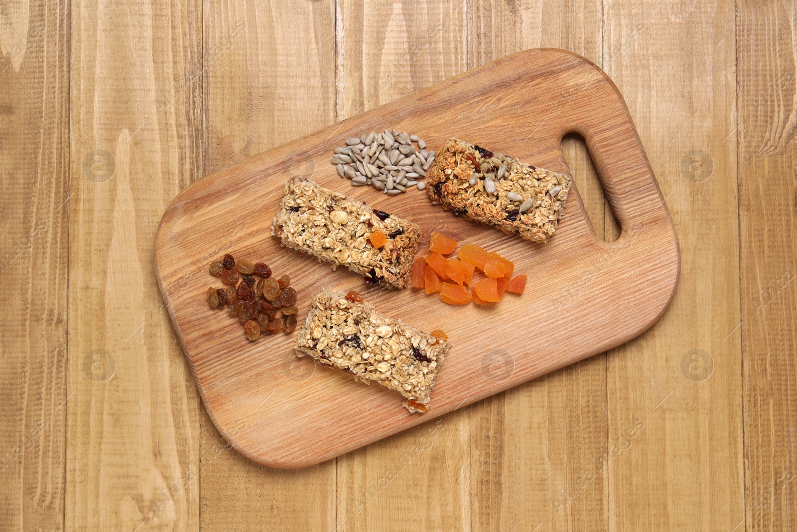 Photo of Different tasty granola bars and ingredients on wooden table, top view