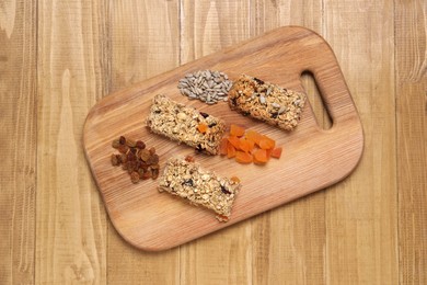 Different tasty granola bars and ingredients on wooden table, top view